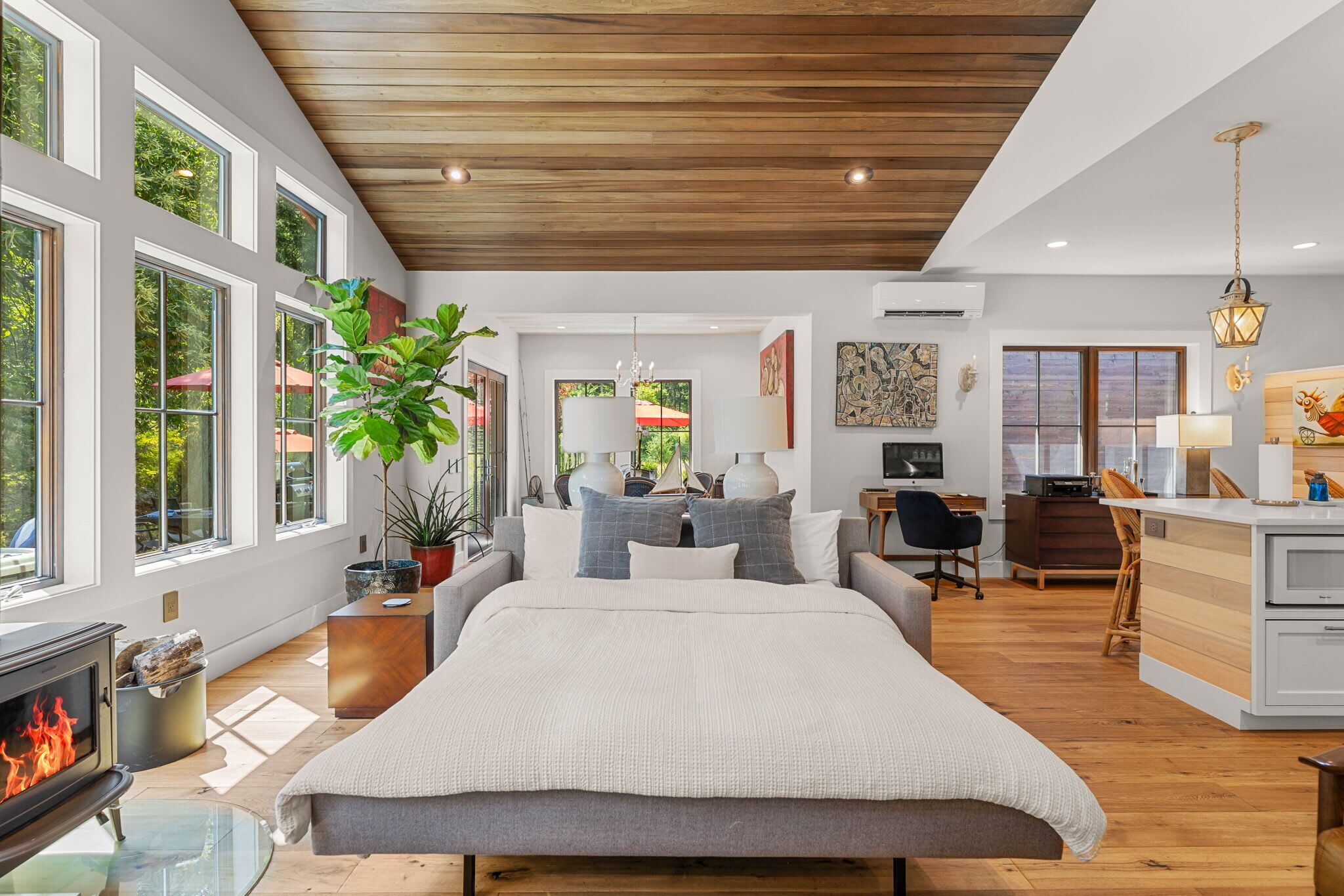 A modern bedroom with a large bed, a fireplace, and a view of the outdoors.