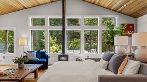A spacious living room with a large bed, a blue sofa, a wooden coffee table, and a fireplace. - Modern Gorge Retreat • Hot Tub • Mountain Views (Cascade Locks)