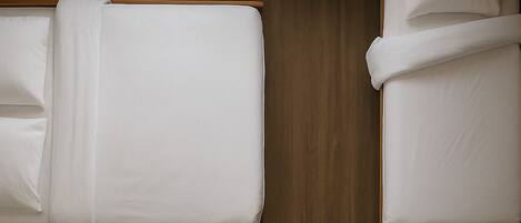 Une chambre d’hôtel avec deux lits, des murs en bois et un luminaire au plafond.