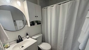 Et badeværelse med hvid vask, toilet og bruseforhæng.