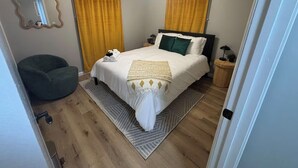 Et soveværelse med seng, loftventilator, natbord og stol.