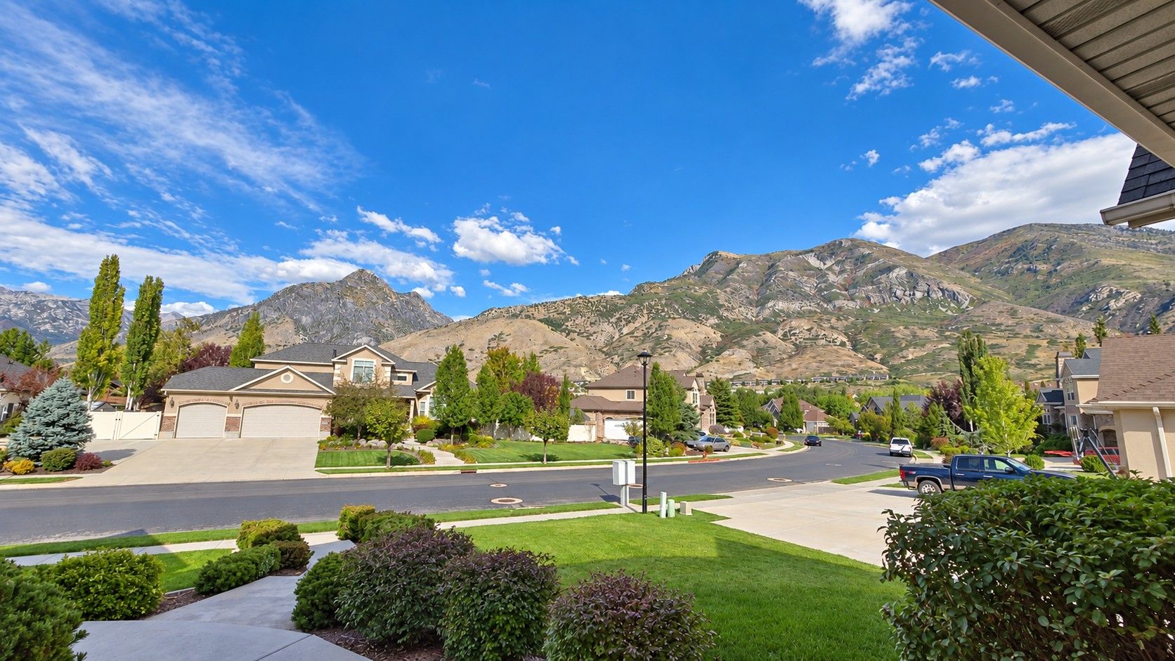 A residential street with houses, a clear sky, and mountains in the background.
