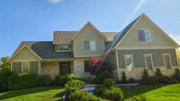 A two-story house with a stone foundation, a front porch, and a well-maintained lawn.