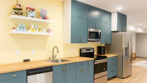 Eine moderne Küche mit türkisfarbenen Schränken, Edelstahlgeräten und einer Holz Arbeitsplatte.