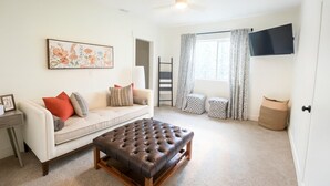 Ein Wohnzimmer mit Sofa, Hocker und einem Gemälde an der Wand.