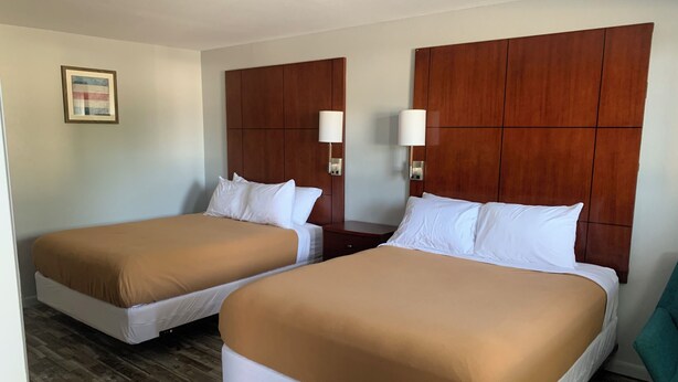 A hotel room with two beds, wooden headboards, bedside lamps, and a framed picture on the wall. - Newly remodeled 14-room hotel in charming St. Mary's . (St. Marys)