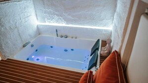 A small, enclosed hot tub with a wooden floor and a statue beside it. - Suite with private spa in the heart of Palermo✨️ (Palermo)