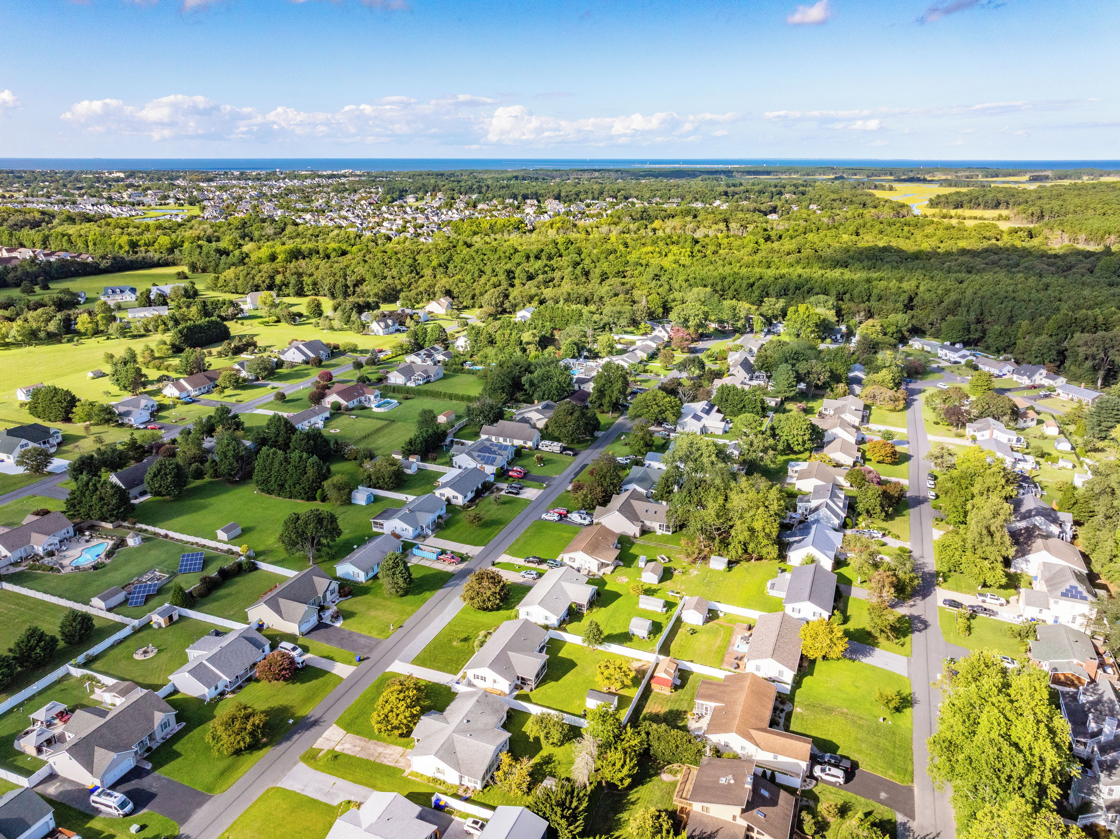 Een woonwijk met huizen, groene gazons en een heldere lucht.