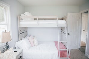 Ein Schlafzimmer mit Etagenbett, Fenster, Nachttisch und Tür.