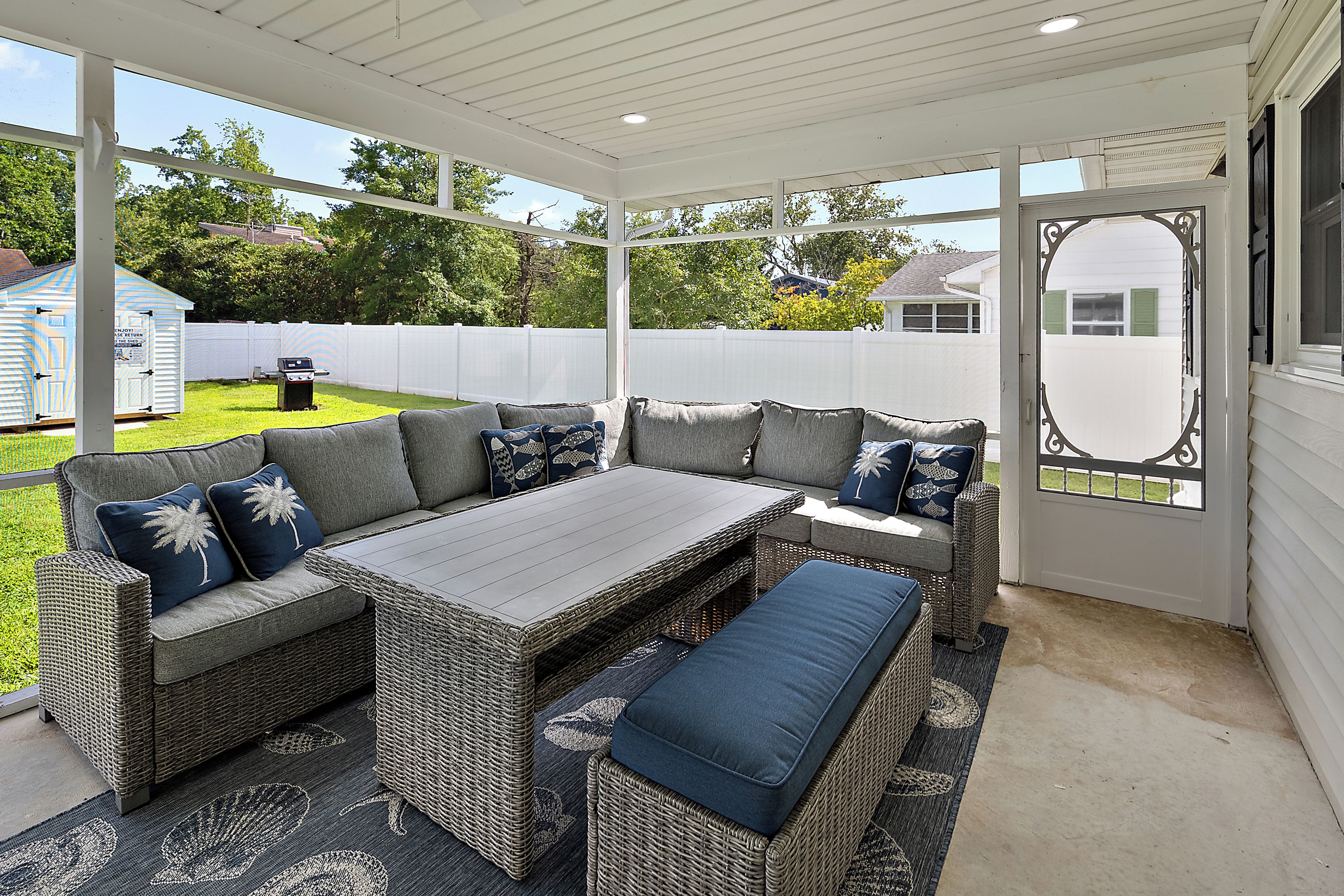 An outdoor patio with a sectional sofa, a dining table, and a bench.