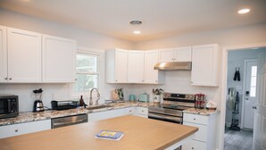 A modern kitchen with white cabinets, a granite countertop, stainless steel appliances, and a wooden island. - 4BR Beach House Sleeps 12/Screened Porch/Parking for 6 cars /Rehoboth (Rehoboth Beach)