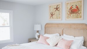 A bedroom with a wooden bed, white bedding, a nightstand with a lamp, and two framed pictures on the wall. - 4BR Beach House Sleeps 12/Screened Porch/Parking for 6 cars /Rehoboth (Rehoboth Beach)