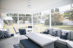 Ein überdachter Außenbereich mit einer Couch, Stühlen und einem Tisch.