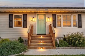 Una casa con puerta verde, escalones de madera y buzón.