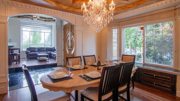 A dining area with a chandelier, large windows, and a view of the outdoors.