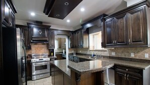 A modern kitchen with dark wood cabinets, stainless steel appliances, and a granite countertop.
