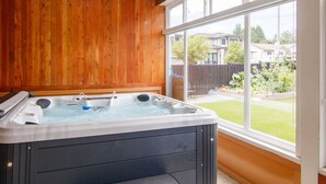 A hot tub in a room with wooden walls and large windows.