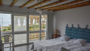 A bedroom with a large bed, a view of the outdoors, and a chair by the window. - Casa Paracas by Wynwood House (Paracas)