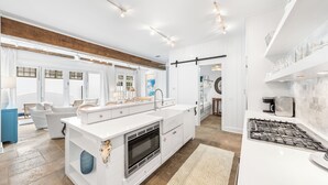 A modern kitchen with white cabinetry, a central island, and a stove.