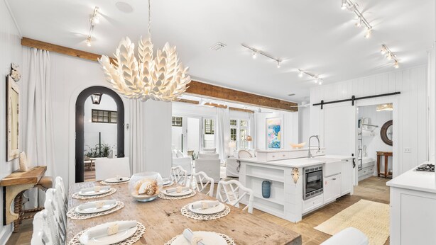 A modern kitchen with white cabinetry, a wooden island, and a dining area with a wooden table set for four.