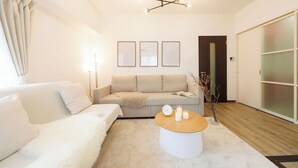 A modern living room with a sofa, a coffee table, and a chandelier. - Baggage OK！Clean, Comfy bed Stay- Dotombori Haven (大阪市中央区島之内2丁目)