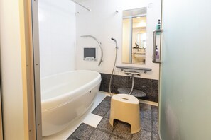 A bathroom with a white bathtub, a handheld showerhead, a small step stool, and a digital control panel. - Baggage OK！Clean, Comfy bed Stay- Dotombori Haven (大阪市中央区島之内2丁目)
