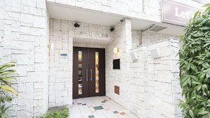 A building entrance with a stone facade, a sign above the door, and a small plant to the right. - Baggage OK！Clean, Comfy bed Stay- Dotombori Haven (大阪市中央区島之内2丁目)