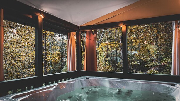 Un jacuzzi con vistas al follaje otoñal a través de amplias ventanas.