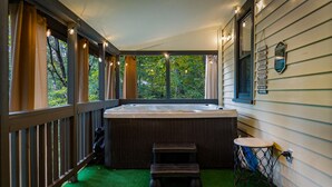 Un área de hidromasaje con terraza de madera, un taburete pequeño y una guirnalda de luces.