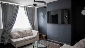Un salon avec un canapé, une table basse en verre et un téléviseur fixé au mur.