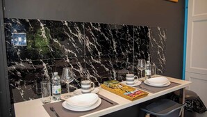 Un coin repas agrémenté d’un pare-feu en marbre, d’une table mise avec des assiettes, des verres et des couverts, et d’une poubelle placée sur le côté.
