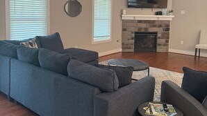 Una sala de estar con un sofá gris, una chimenea y un televisor montado encima.