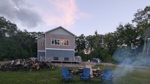 Takapihalla on nuotiopaikka, ulkokalusteita ja taustalla näkyy talo.