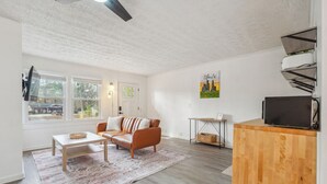 A modern living room with a sofa, coffee table, and a TV on a wooden cabinet.