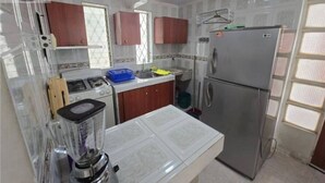 Una cucina con frigorifero, fornello e frullatore sul piano di lavoro.