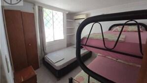 Una camera da letto con letti a castello, un armadio, una finestra e un tavolino.