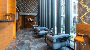 A modern lobby with a patterned wall, a fireplace, and a seating area with a view of the outdoors. - Infinity Sky Pool Walk to BeachC182 (Kamala)