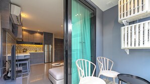 A modern kitchen with a built-in oven, a dining area with a table and chairs, and a sliding glass door leading to a balcony. - Infinity Sky Pool Walk to BeachC182 (Kamala)