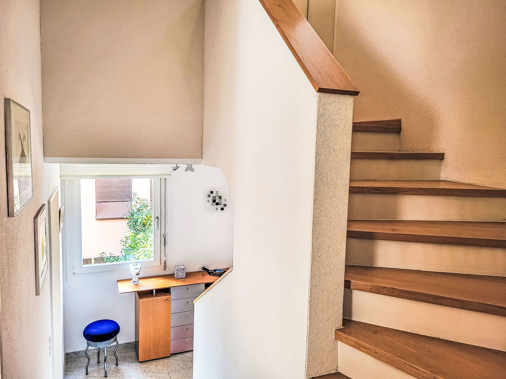 A staircase with wooden steps and a handrail, leading to a landing with a desk and chair.