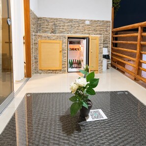 A room with a stone wall, a wooden door, a refrigerator with bottles, and a potted plant on a woven mat. - Casa 4 habs con aire, piscina y mar a 50 pasos (Zorritos District)