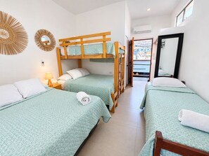 Habitación de hotel con literas, una lámpara de noche, un espejo y vistas al exterior.