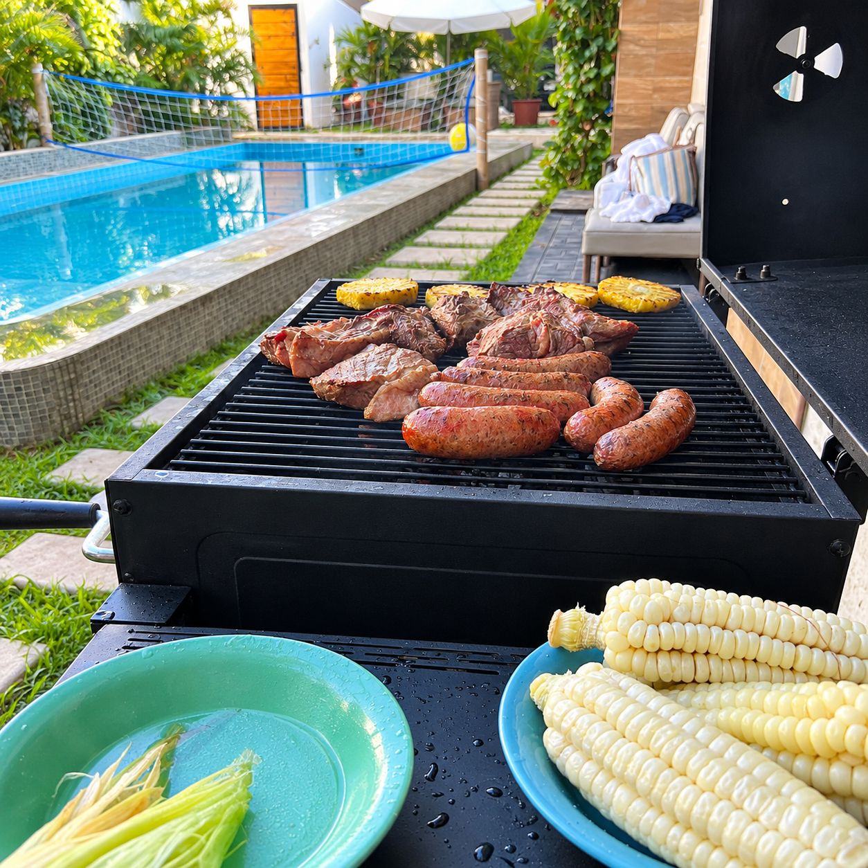 A barbecue grill with various meats and vegetables, a pool in the background, and outdoor furniture.