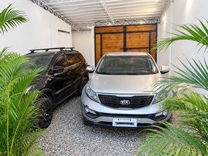 Two cars parked inside a garage with a wooden door and metal beams on the ceiling. - Casa 4 habs con aire, piscina y mar a 50 pasos (Zorritos District)