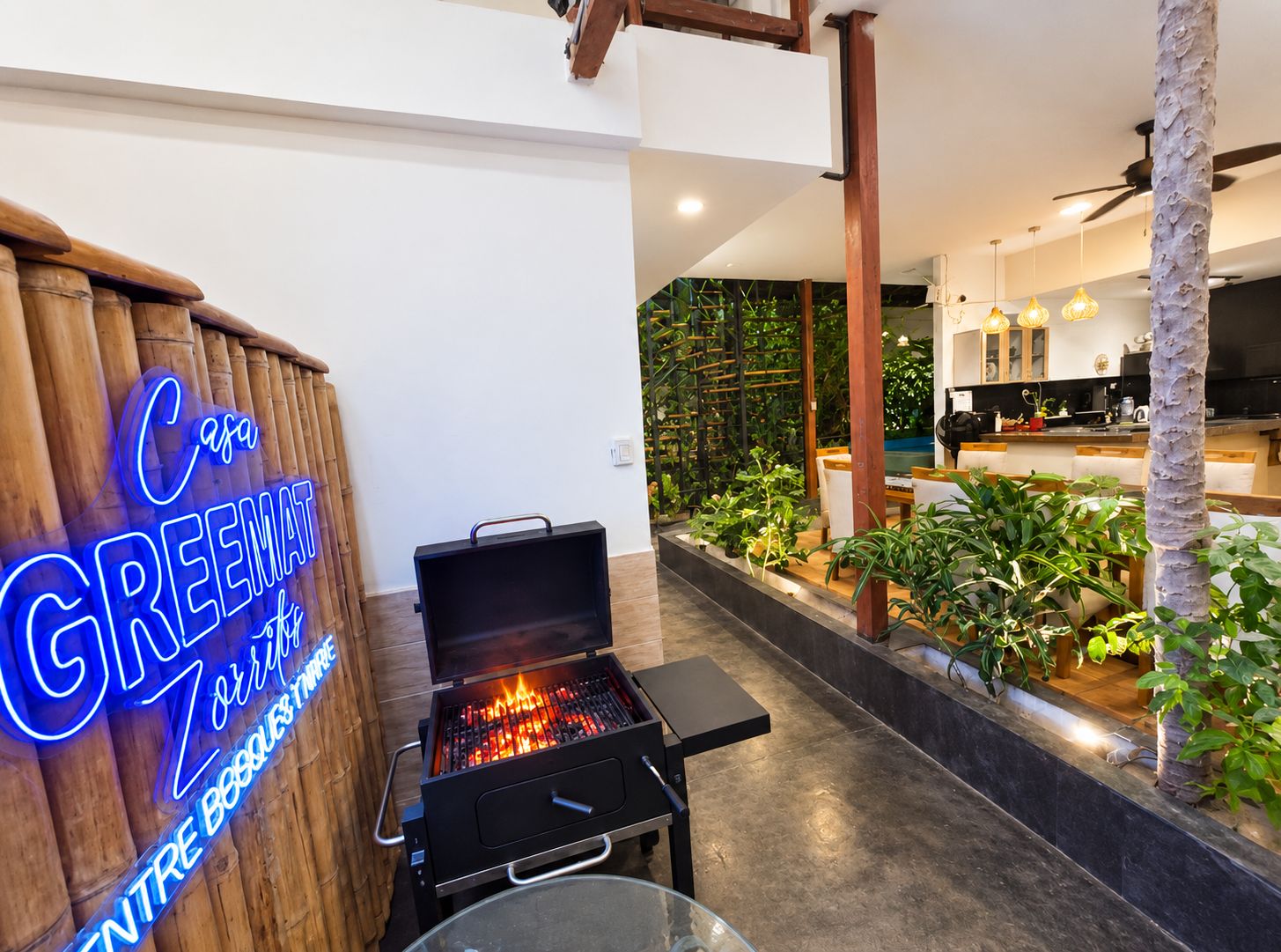 Una cocina moderna con una parrilla integrada, un letrero de neón y vistas a un jardín exuberante.
