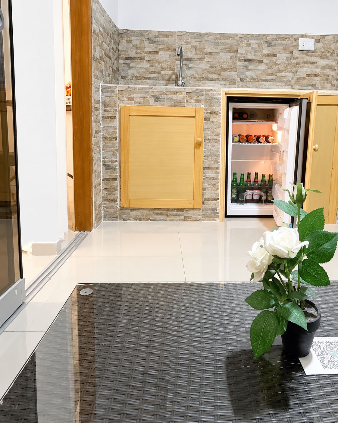 Eine moderne Küche mit einem eingebauten Kühlschrank, einem Holzkasten und einem Blumentopf auf einem Glastisch.