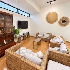 A modern living room with wicker furniture, a flat-screen TV, and decorative wall art. - Casa 4 habs con aire, piscina y mar a 50 pasos (Zorritos District)