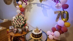 A birthday party setup with a cake, balloons, and a 'Happy 70th Birthday' banner.