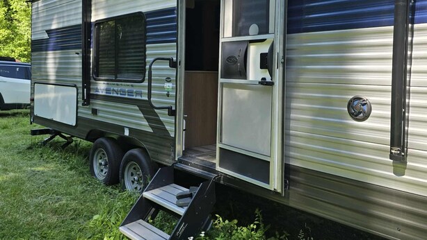 A motorhome with a sliding door, a small step-up ramp, and a window on the side.