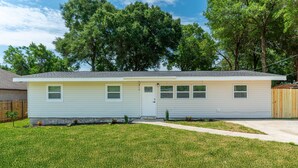 A single-story house with a front door, a small porch, and a well-maintained lawn. - THE GARDEN HOUSE (Fort Walton Beach)