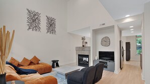 Un salon moderne avec une cheminée, un canapé et un téléviseur.